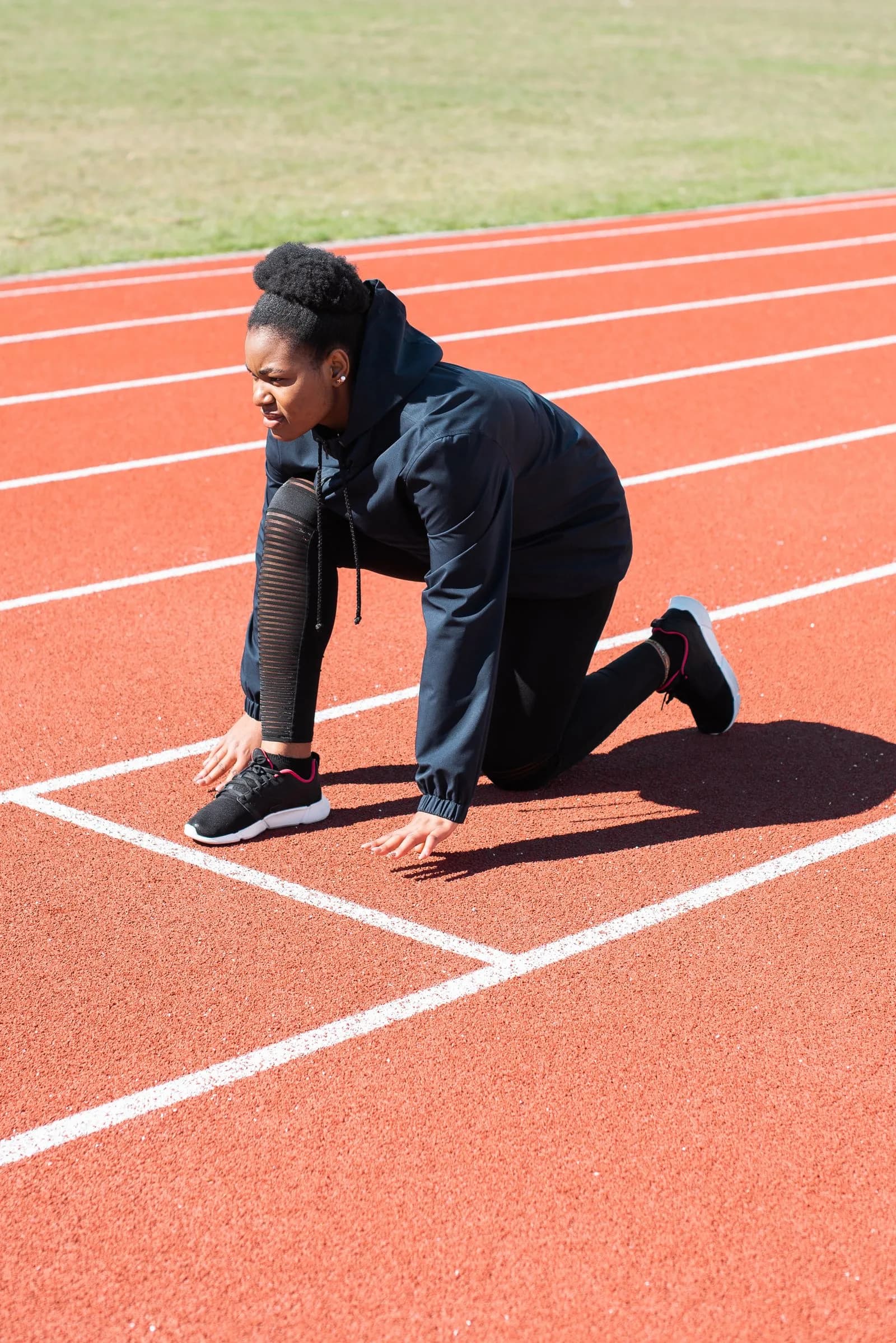 An athlete preparing to start a sprint on an outdoor track.